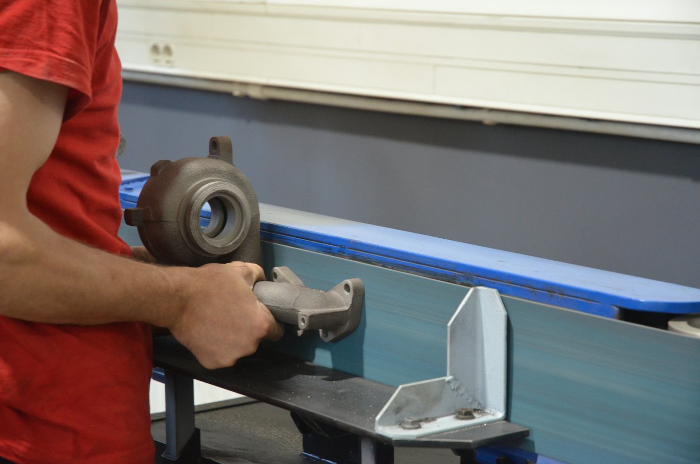 Person grinding automotive parts on a belt sander.