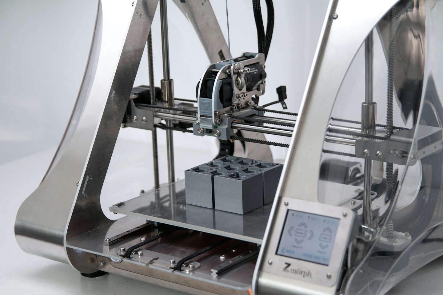 A 3D printer creating grey objects on its platform.